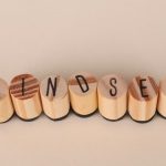Wooden letter stamps spelling 'Mindset' on a simple beige background, conveying focus and positive thinking.